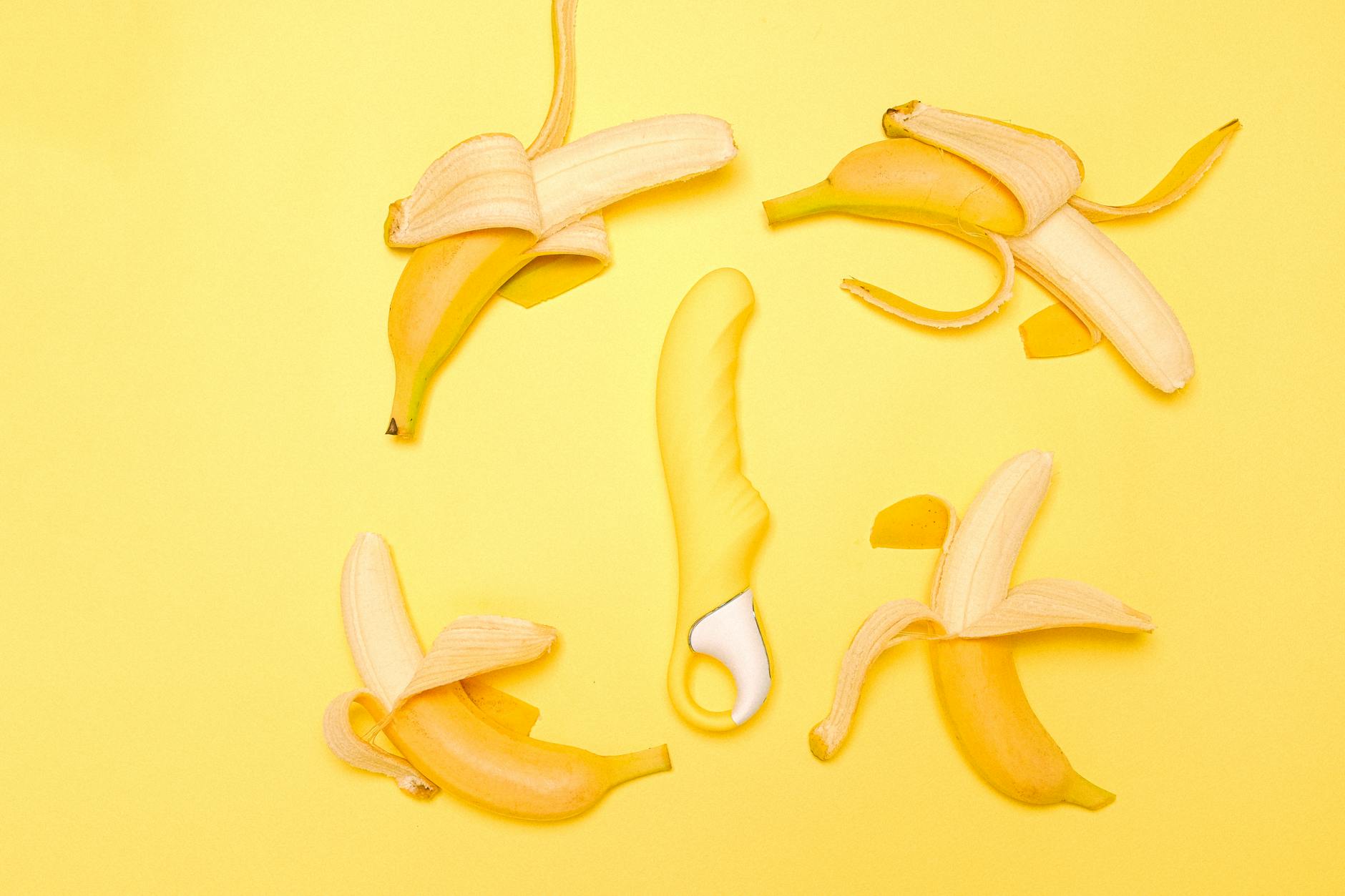 Yellow silicone lemon vibrator on a bright yellow background with fresh lemon slices