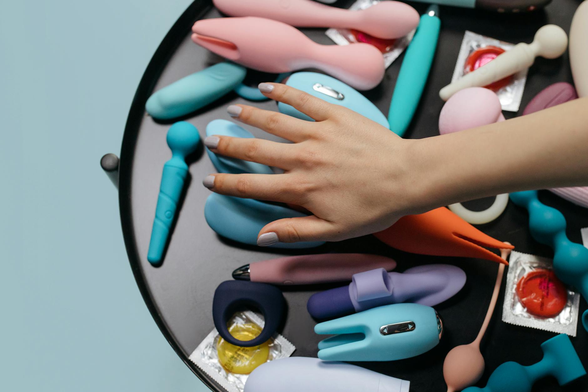 Close-up of a hand holding a lemon clitoral vibrator with personal items in soft focus, representing intimate communication and new experiences with a partner.