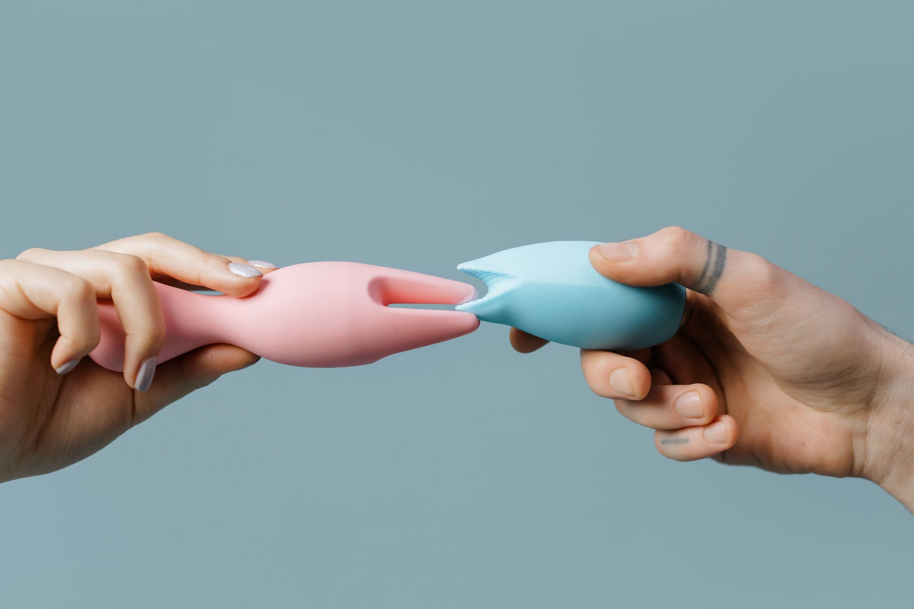 Hands holding a blue personal massager against a knitted sweater, representing solo self-care and intimate exploration.